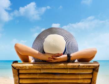 woman in hat relaxing on beach lounger