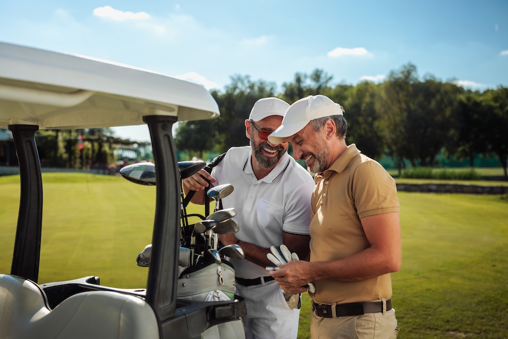 two men standing by golf cart